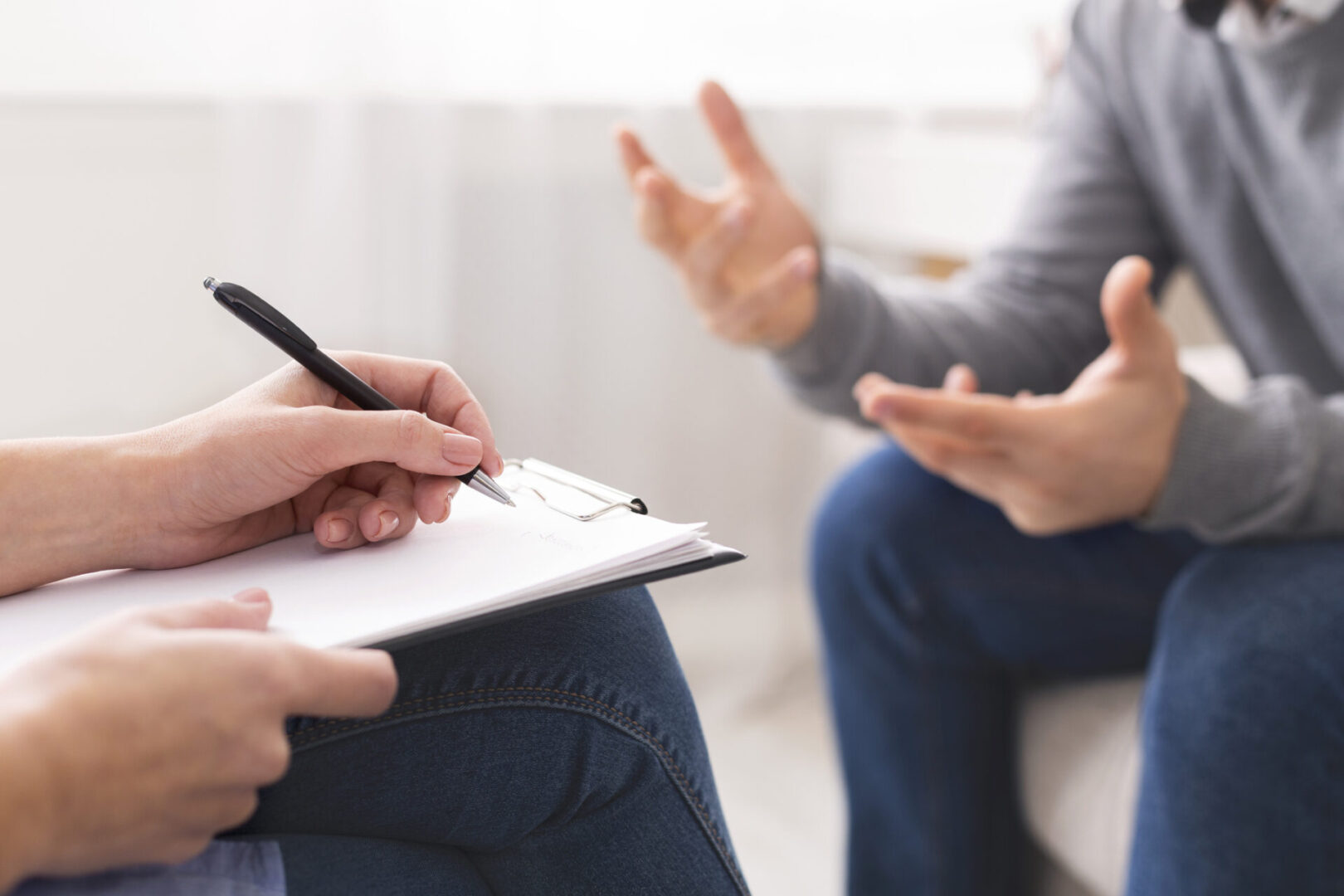 Two people sitting on a couch talking to each other.